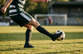 Soccer player striking the ball with the laces, plant foot planted beside the ball