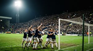 Estadio lleno de noche mientras un equipo celebra ante la grada