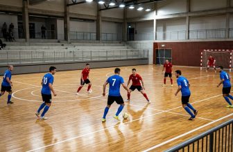 Futsal teams in position on an indoor court during a match, seen from the stand