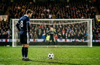 Player standing over the ball on the penalty spot with the goalkeeper on the line