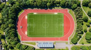 Aerial view of an eight-lane athletics track with a green football pitch inside it