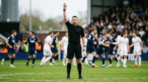 Referee with one arm raised straight above the head signalling an indirect free kick
