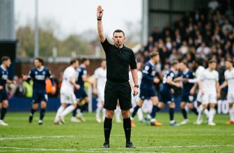 Referee with one arm raised straight above the head signalling an indirect free kick